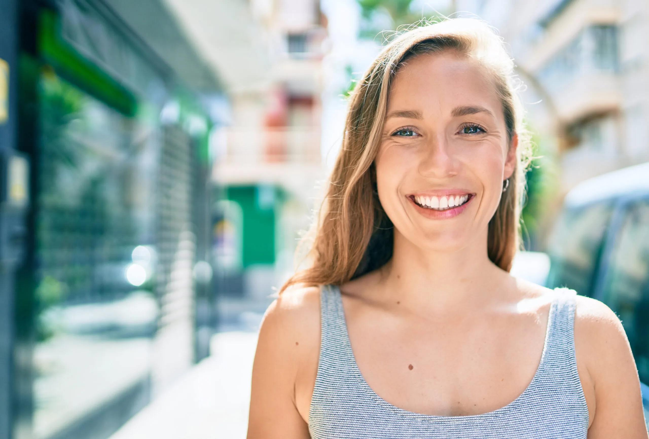 young woman smiling on a city street, perfect white teeth