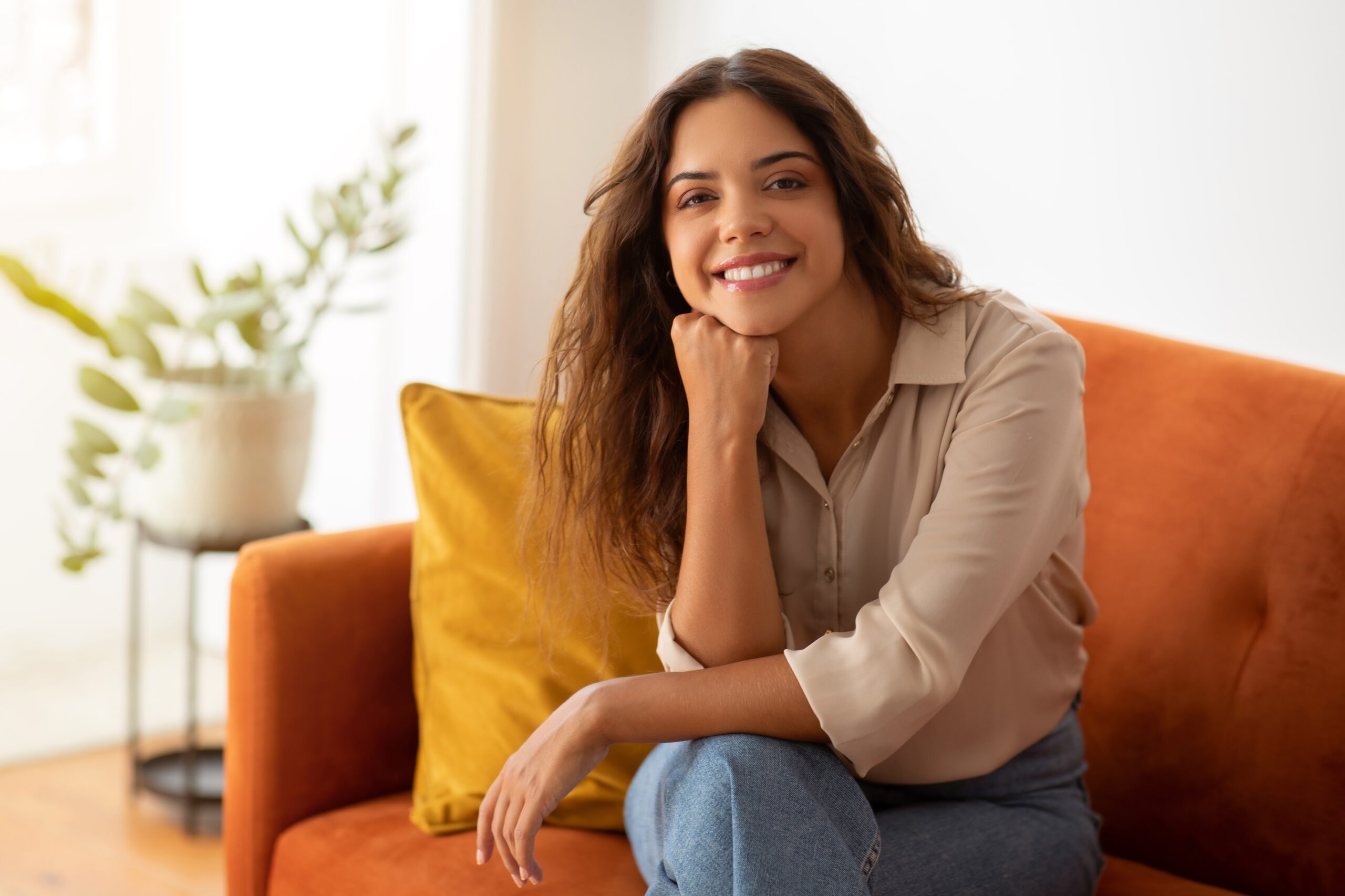 young woman smiling naturally on a orange couch