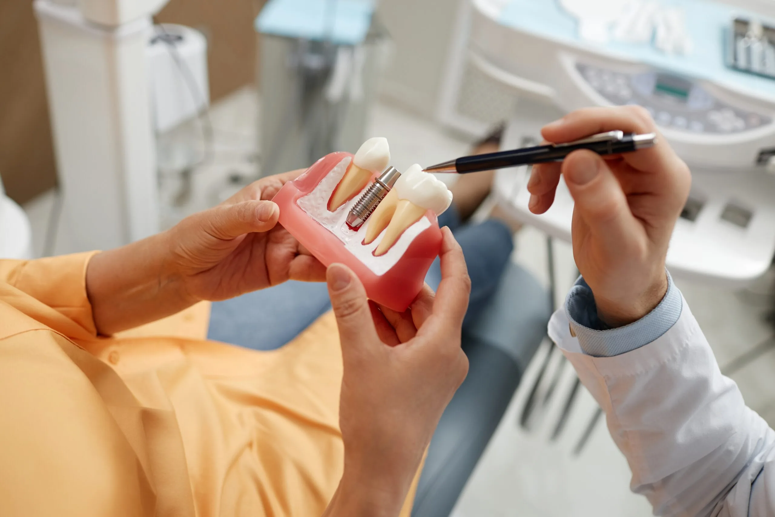 closeup of a dentist showing a patient a dental implant model